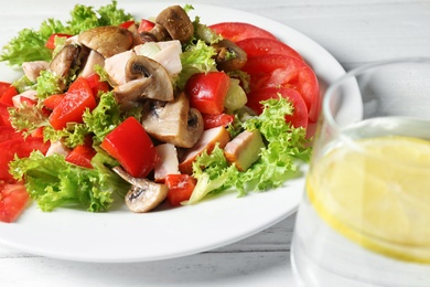 Photo of Plate with delicious fresh salad and glass of drink on table, closeup