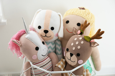 Photo of Funny stuffed toys in basket near white wall. Decor for children's room interior
