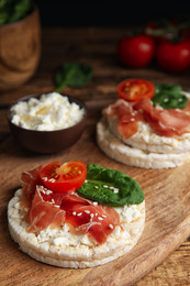 Photo of Puffed rice cakes with prosciutto, tomato and basil on wooden board