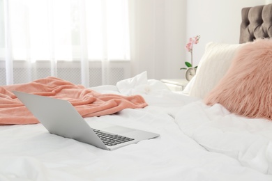 Photo of Laptop on bed in stylish room interior
