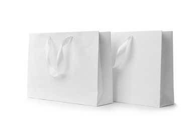 Photo of Paper shopping bags with ribbon handles on white background. Mockup for design