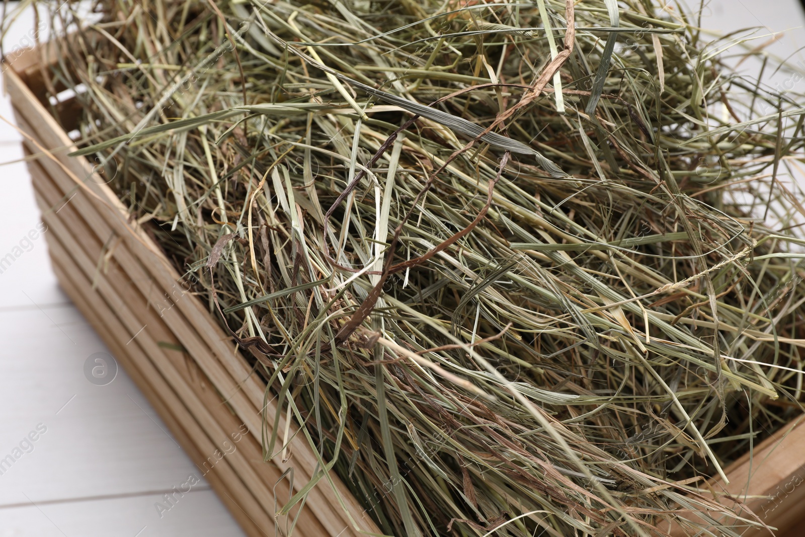 Photo of Crate with dried hay on white wooden table, closeup