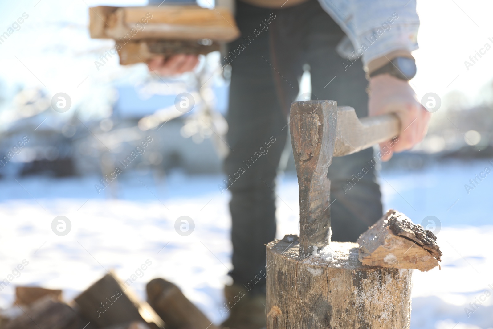 Photo of Man taking axe out of wooden log outdoors on winter day, closeup. Space for text