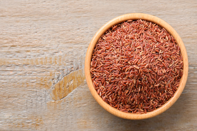 Photo of Brown rice on wooden table, top view. Space for text