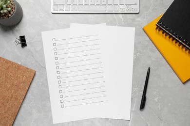 Photo of Paper sheet with checkboxes plant and computer keyboard on light grey marble table, flat lay. Checklist