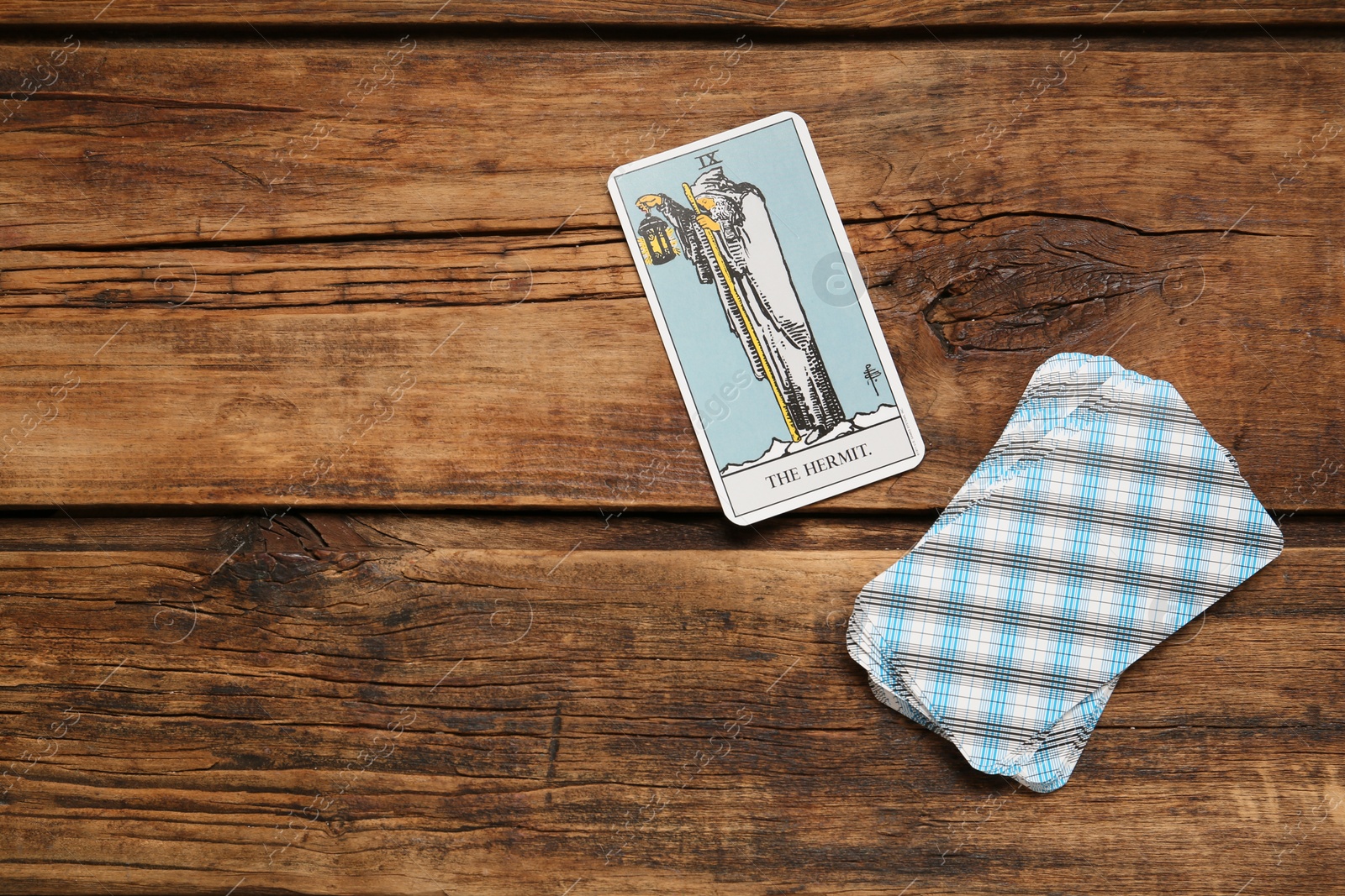 Photo of The Hermit and other tarot cards on wooden table, flat lay. Space for text