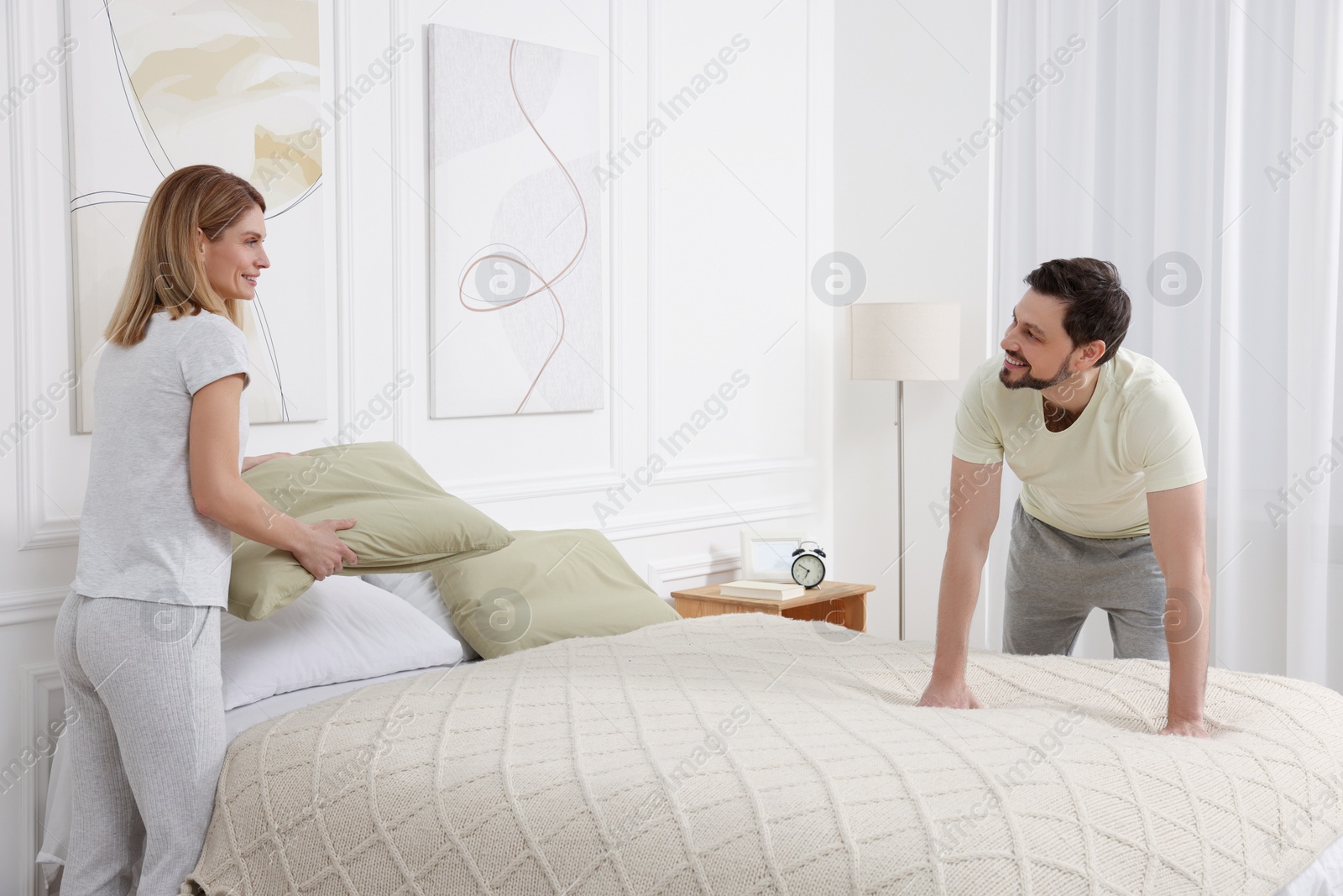 Photo of Couple changing bed linens at home. Domestic chores