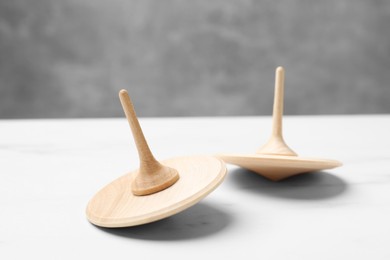 Photo of Two spinning tops on white table, closeup