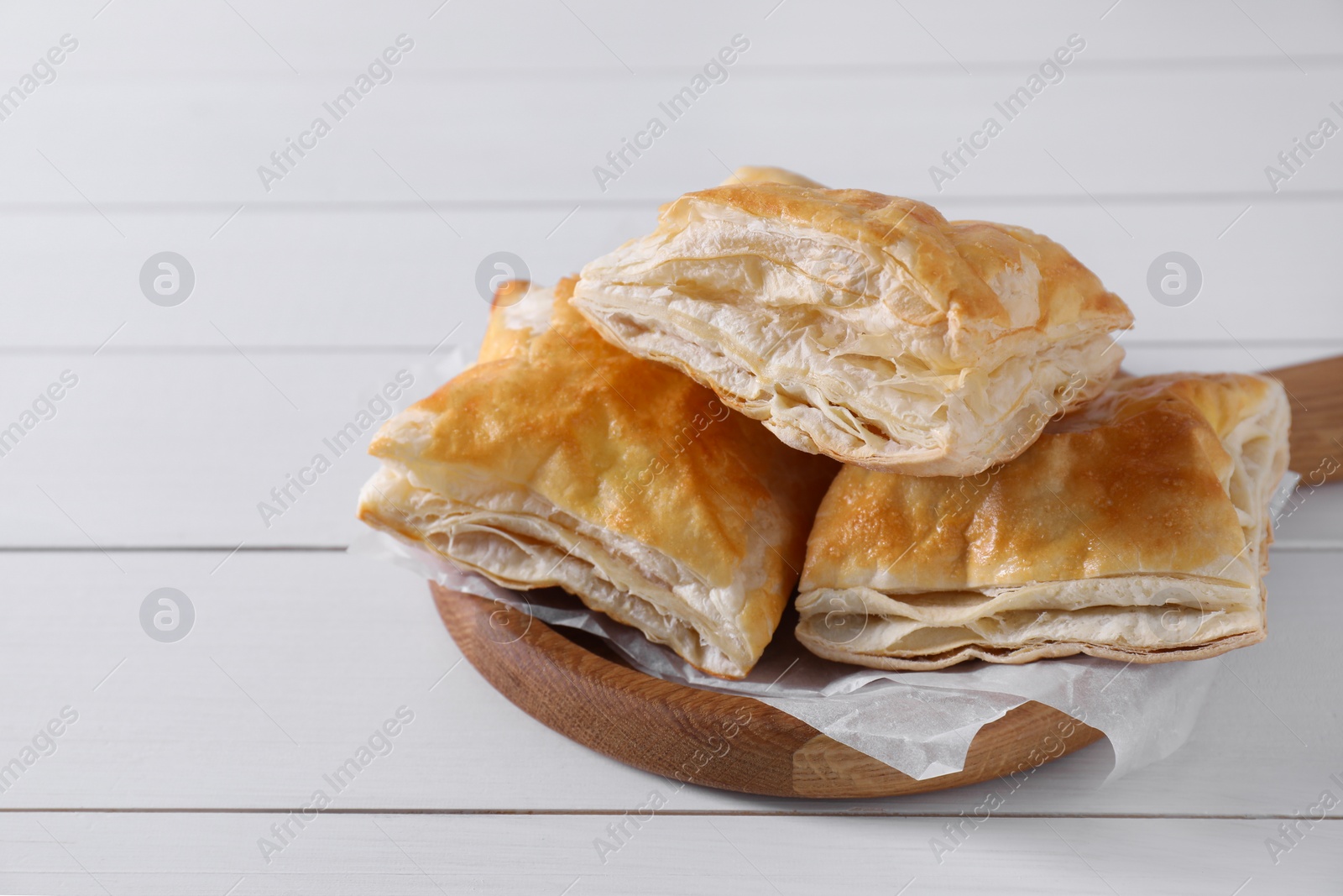 Photo of Delicious puff pastry on white wooden table, closeup. Space for text