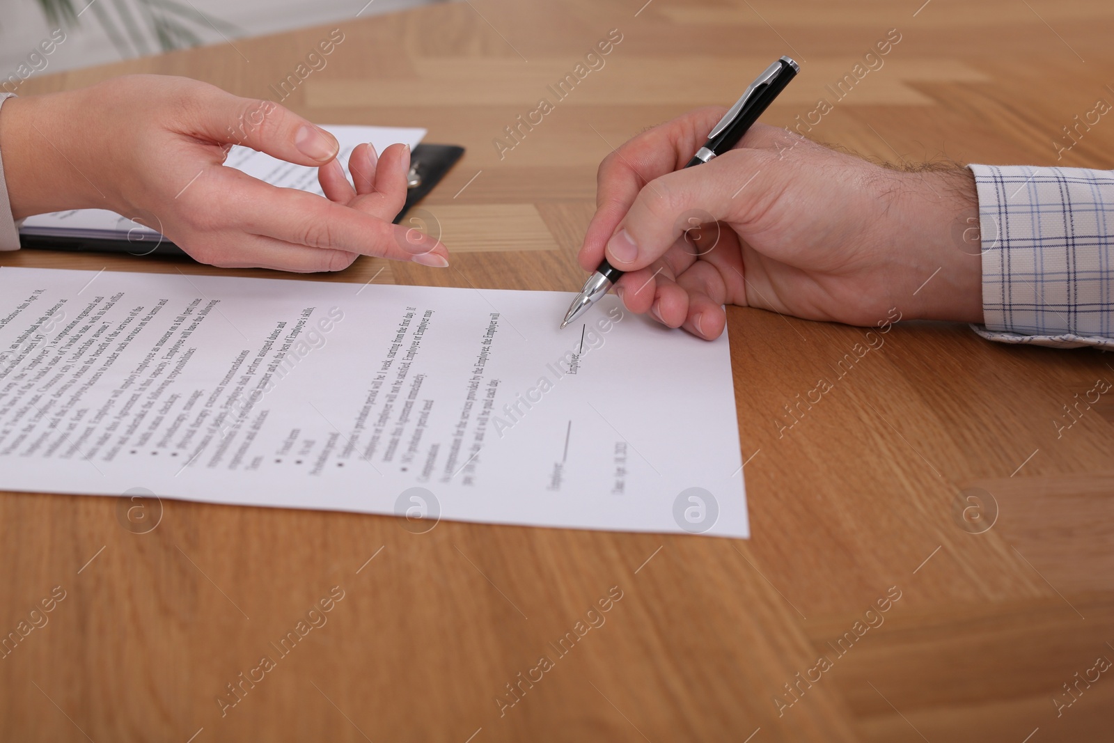 Photo of Businesspeople signing contract at wooden table, closeup of hands