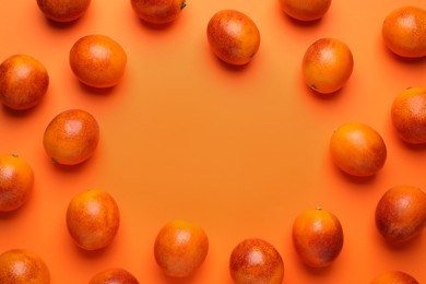 Photo of Frame of ripe sicilian oranges on orange background, flat lay. Space for text