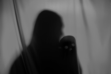 Silhouette of creepy ghost with skull behind grey cloth, space for text