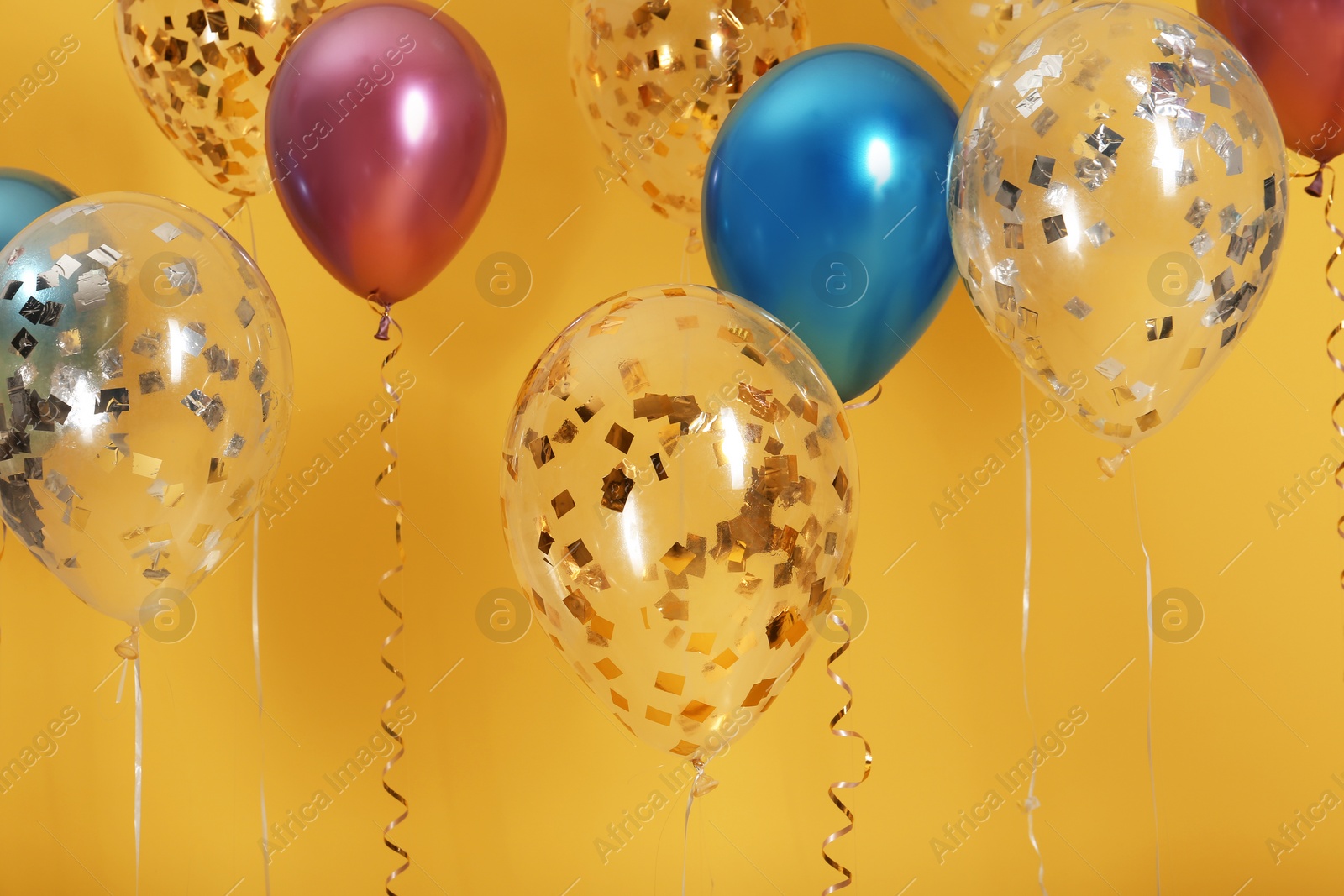 Photo of Bright balloons with ribbons on color background