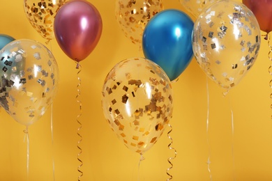 Bright balloons with ribbons on color background