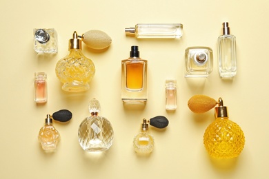 Photo of Flat lay composition with different perfume bottles on light yellow background