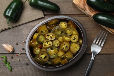 Fresh and pickled green jalapeno peppers on wooden table, flat lay