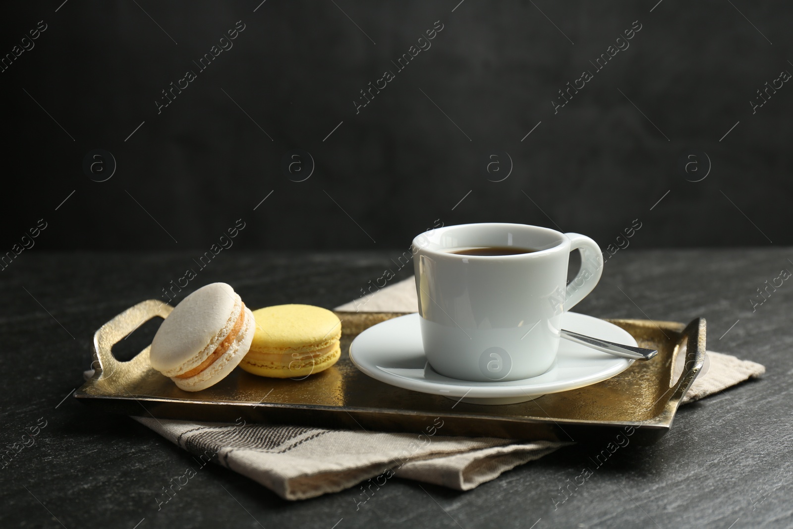 Photo of Tray with hot coffee in cup and macarons on dark textured table