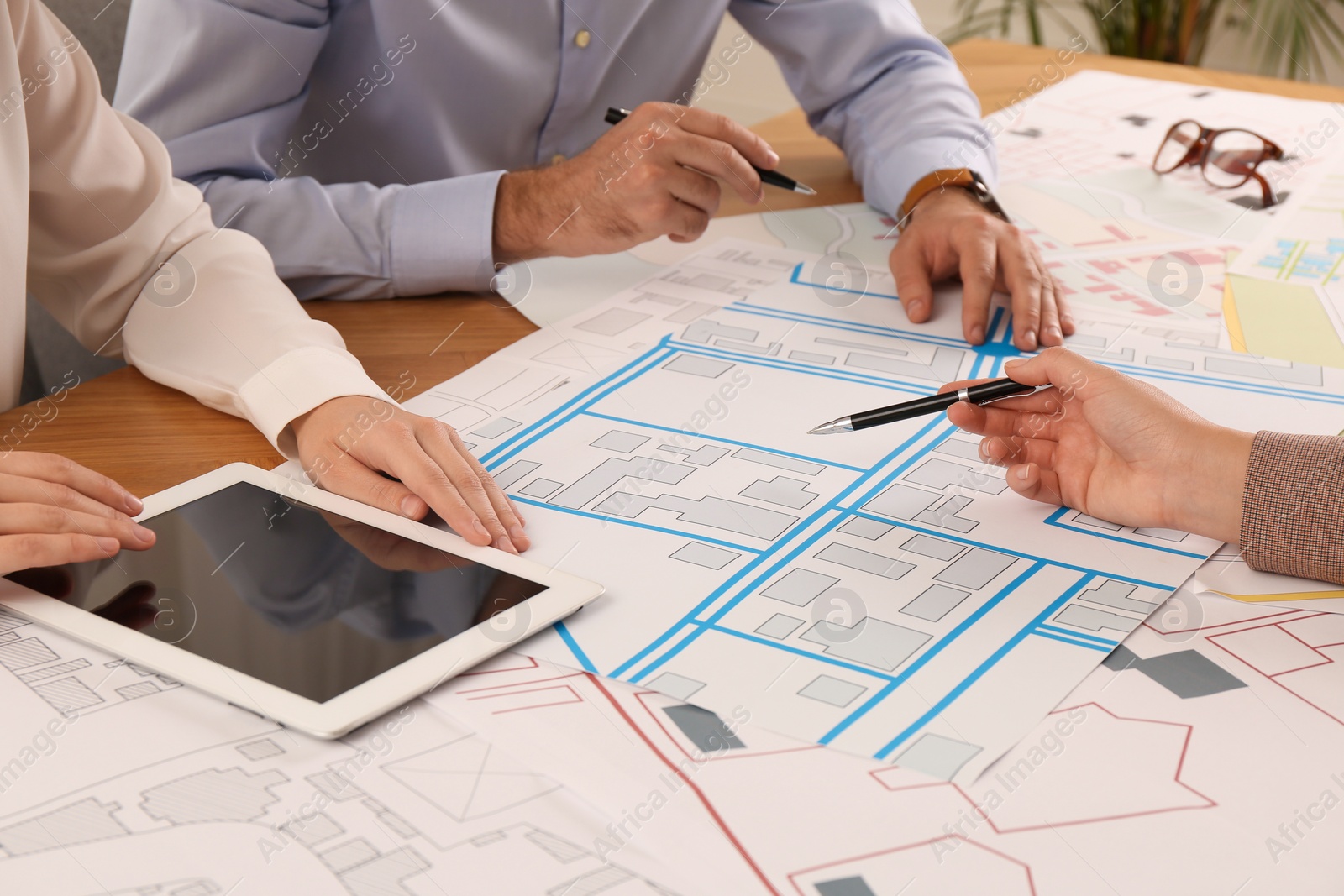 Photo of Professional cartographers working with cadastral map at table, closeup