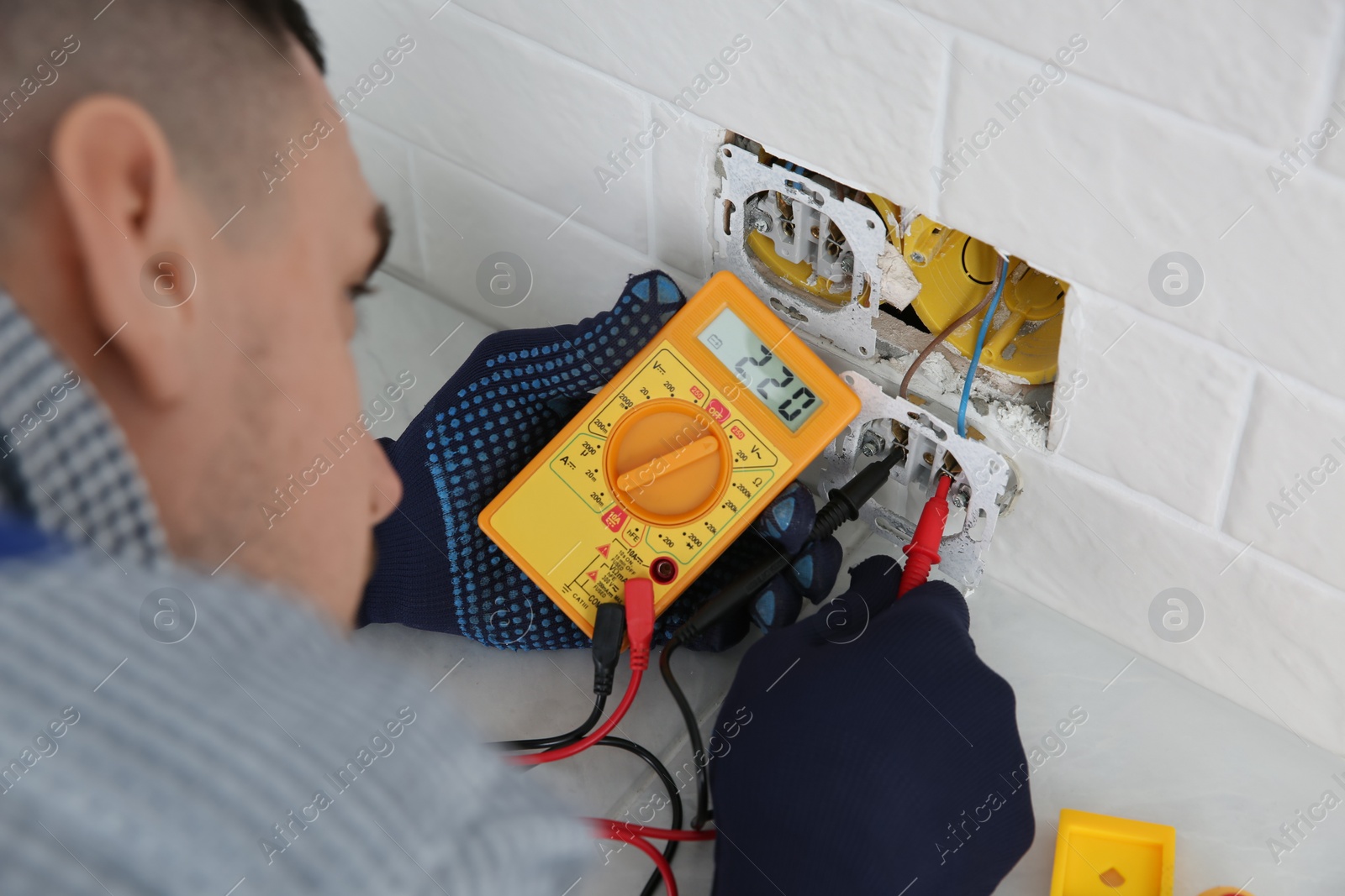 Photo of Electrician with tester checking voltage indoors, closeup