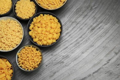 Different types of pasta on grey table, flat lay. Space for text