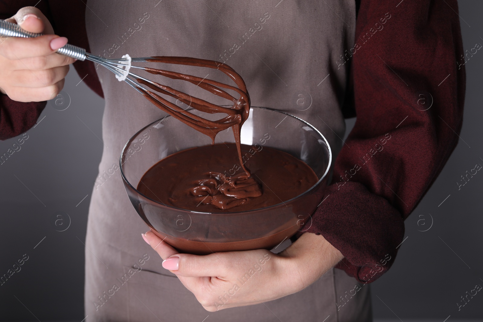 Photo of Woman with whisk making chocolate cream on grey background, closeup