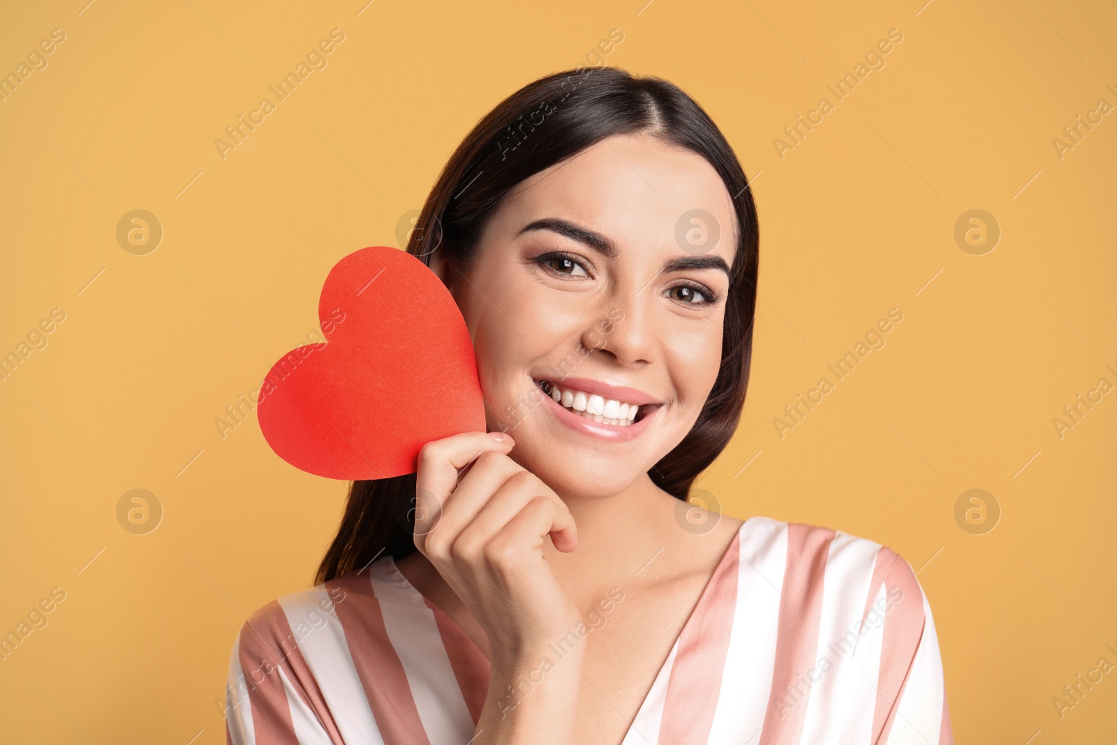 Photo of Portrait of young woman with paper heart on color background