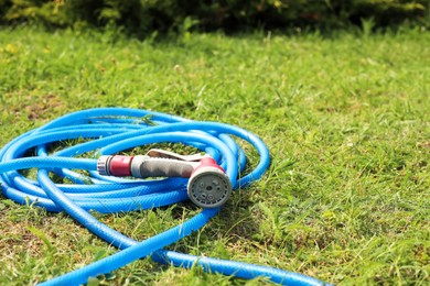 Watering hose with sprinkler on green grass outdoors, space for text