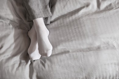 Woman wearing socks on grey blanket, top view. Space for text