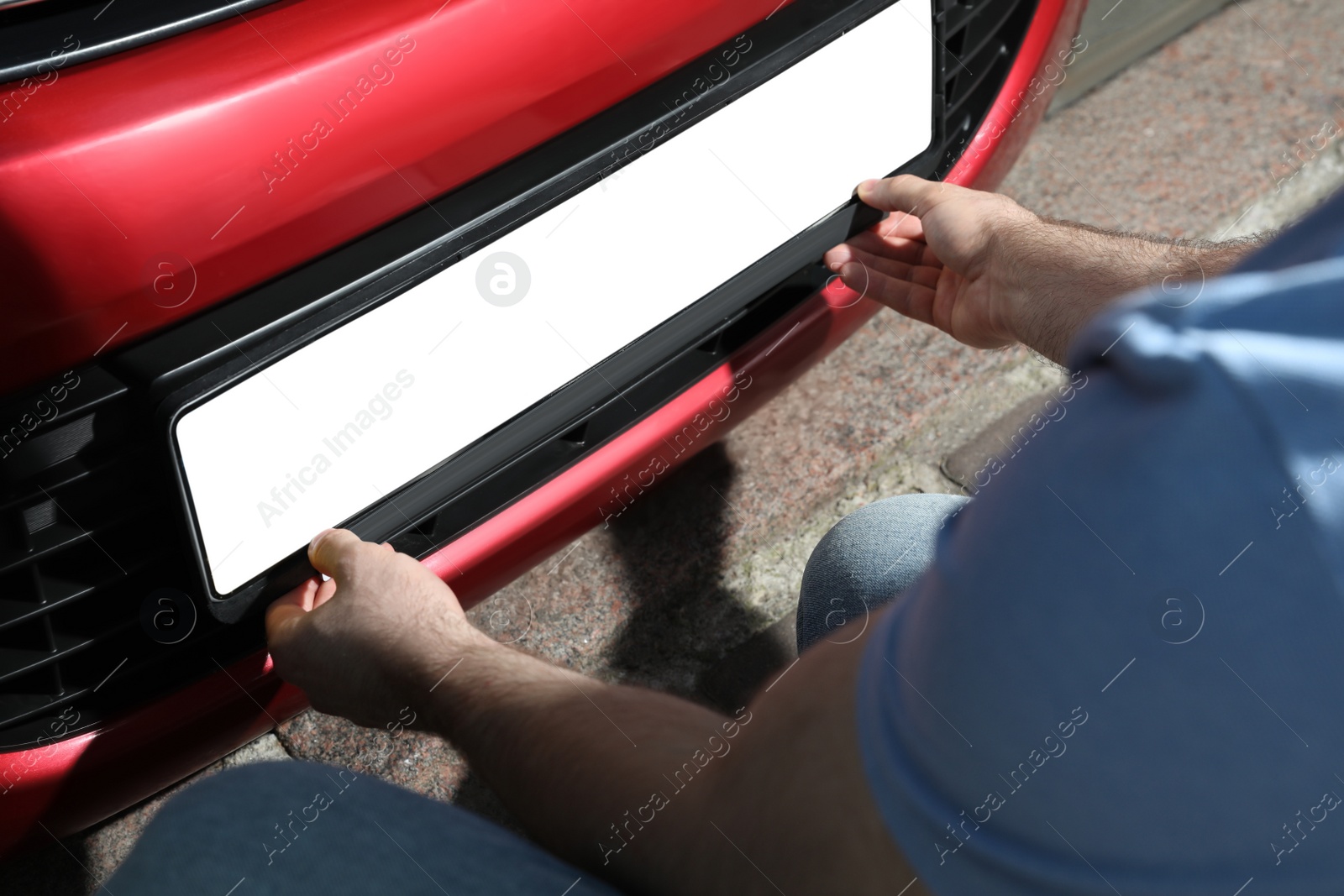 Photo of Man installing vehicle registration plate outdoors, closeup. Mockup for design