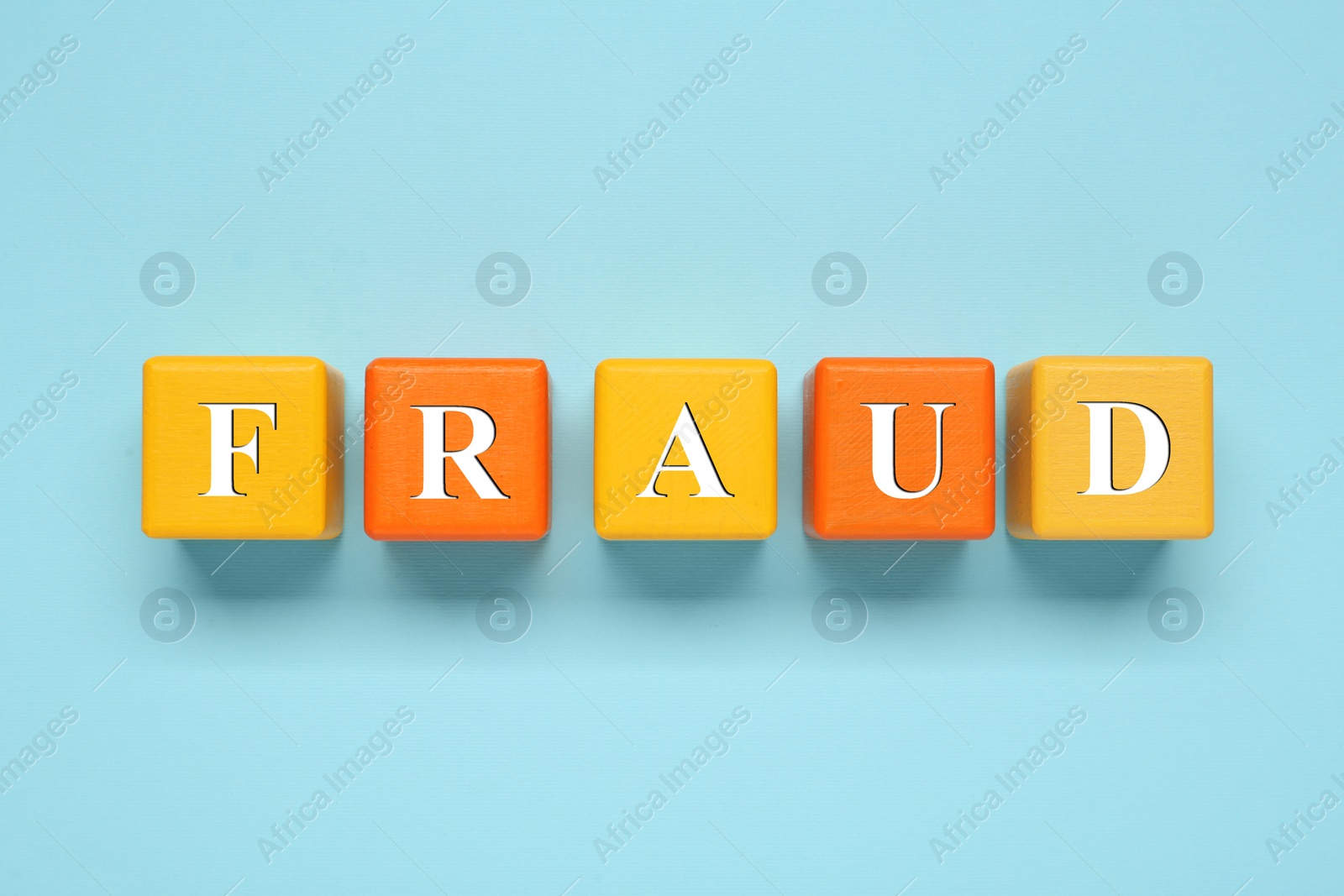 Photo of Word Fraud of wooden cubes with letters on light blue background, flat lay