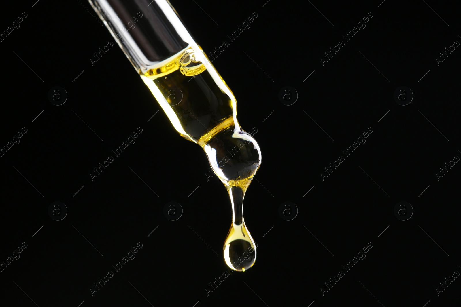 Photo of Dripping tincture from pipette on black background, closeup