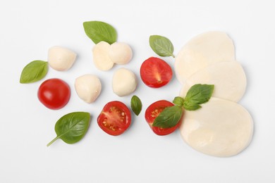 Photo of Mozzarella, tomatoes and basil on white background, flat lay. Caprese salad ingredients