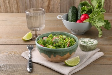 Photo of Delicious salad with radish, lettuce and dill served on wooden table