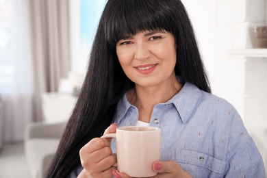 Photo of Beautiful mature woman with cup of drink at home