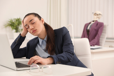 Photo of Young woman sleeping at table and human skeleton on background