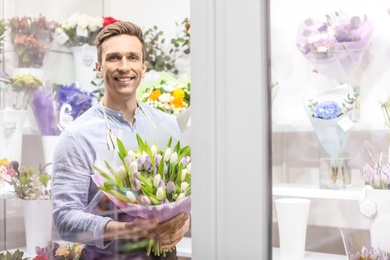 Male florist holding bouquet flowers at workplace