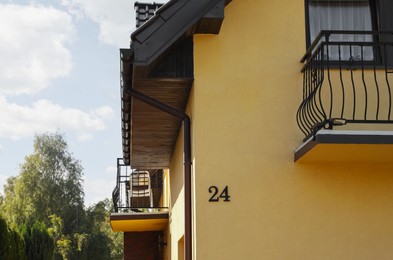 Number 24 on yellow house with balconies outdoors