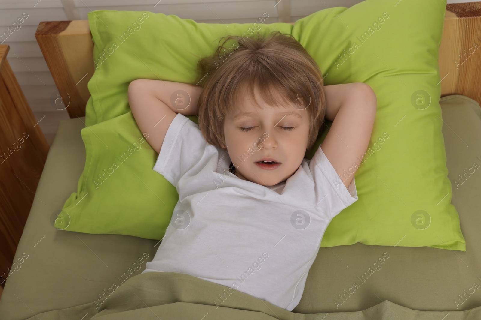 Photo of Little boy snoring while sleeping in bed at home, above view