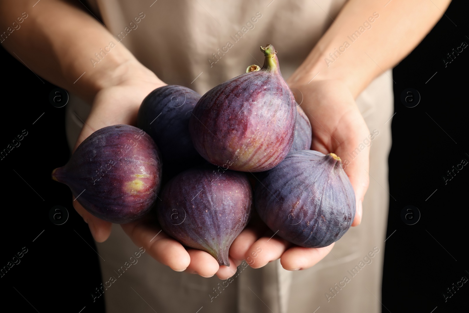 Photo of Woman holding fresh ripe figs on black background