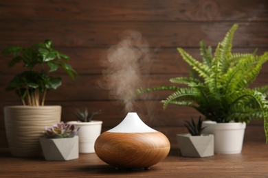 Photo of Composition with modern essential oil diffuser on wooden table against brown background, space for text