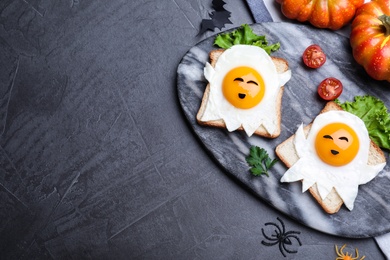 Photo of Halloween themed breakfast served on black table, flat lay and space for text. Tasty toasts with fried eggs in shape of ghost