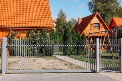 Photo of Closed metal gates near beautiful houses on sunny day
