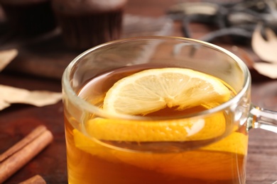 Cup of tasty tea with lemon on table, closeup