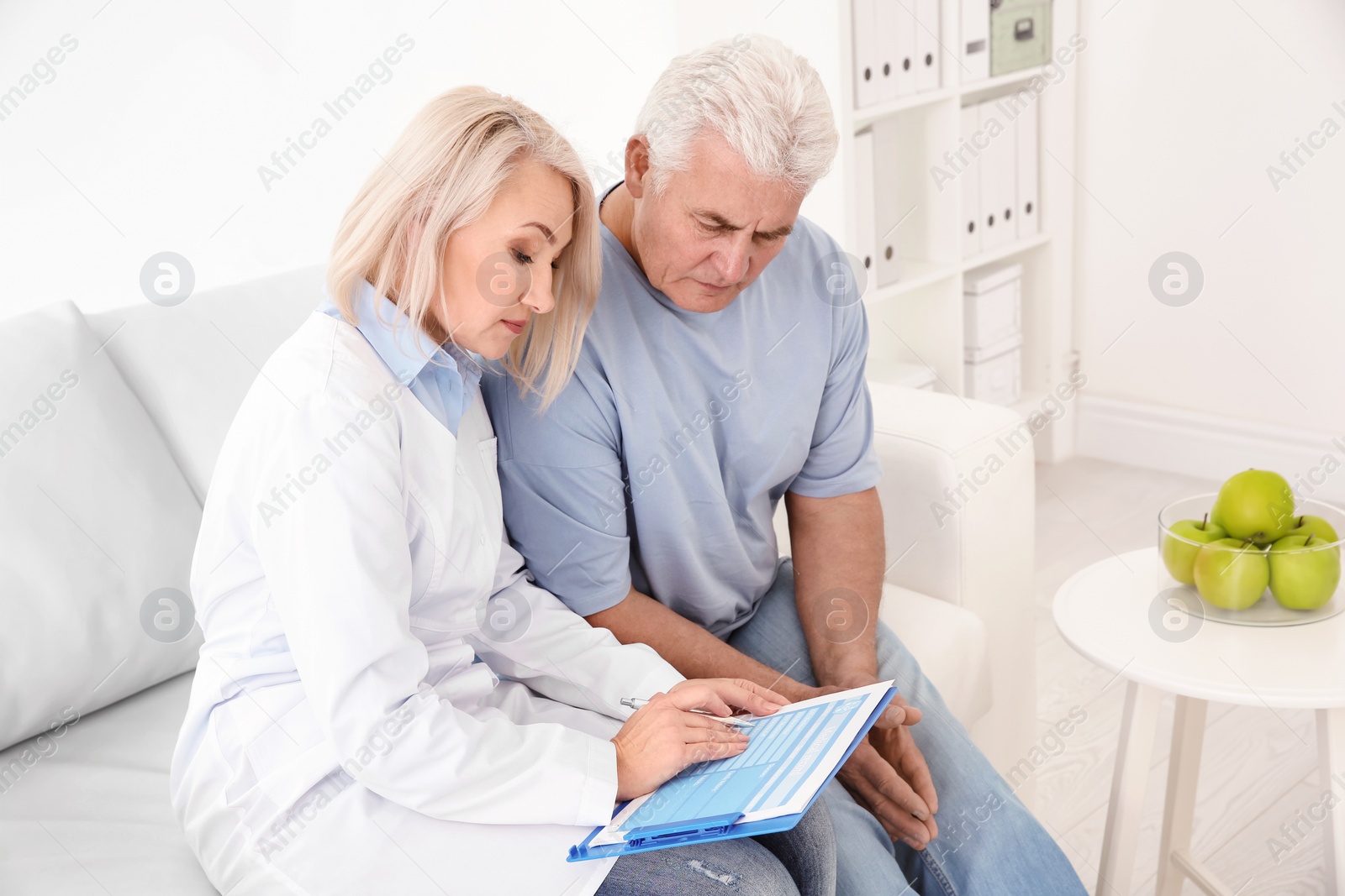 Photo of Senior female receptionist working with client in hospital