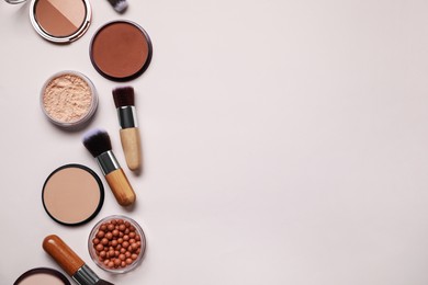 Photo of Different face powders and makeup brushes on light background, flat lay. Space for text