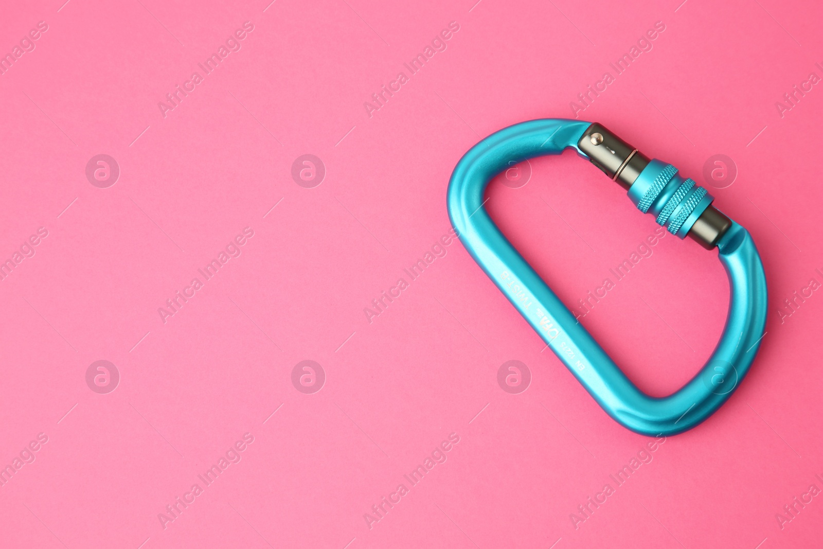 Photo of One metal carabiner on bright pink background, top view. Space for text