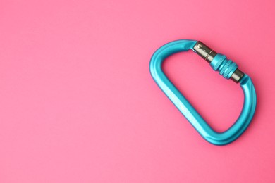 One metal carabiner on bright pink background, top view. Space for text