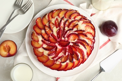 Photo of Delicious cake with plums on light marble table, flat lay