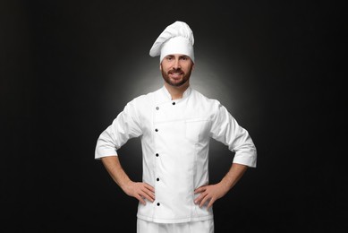 Photo of Smiling mature male chef on black background