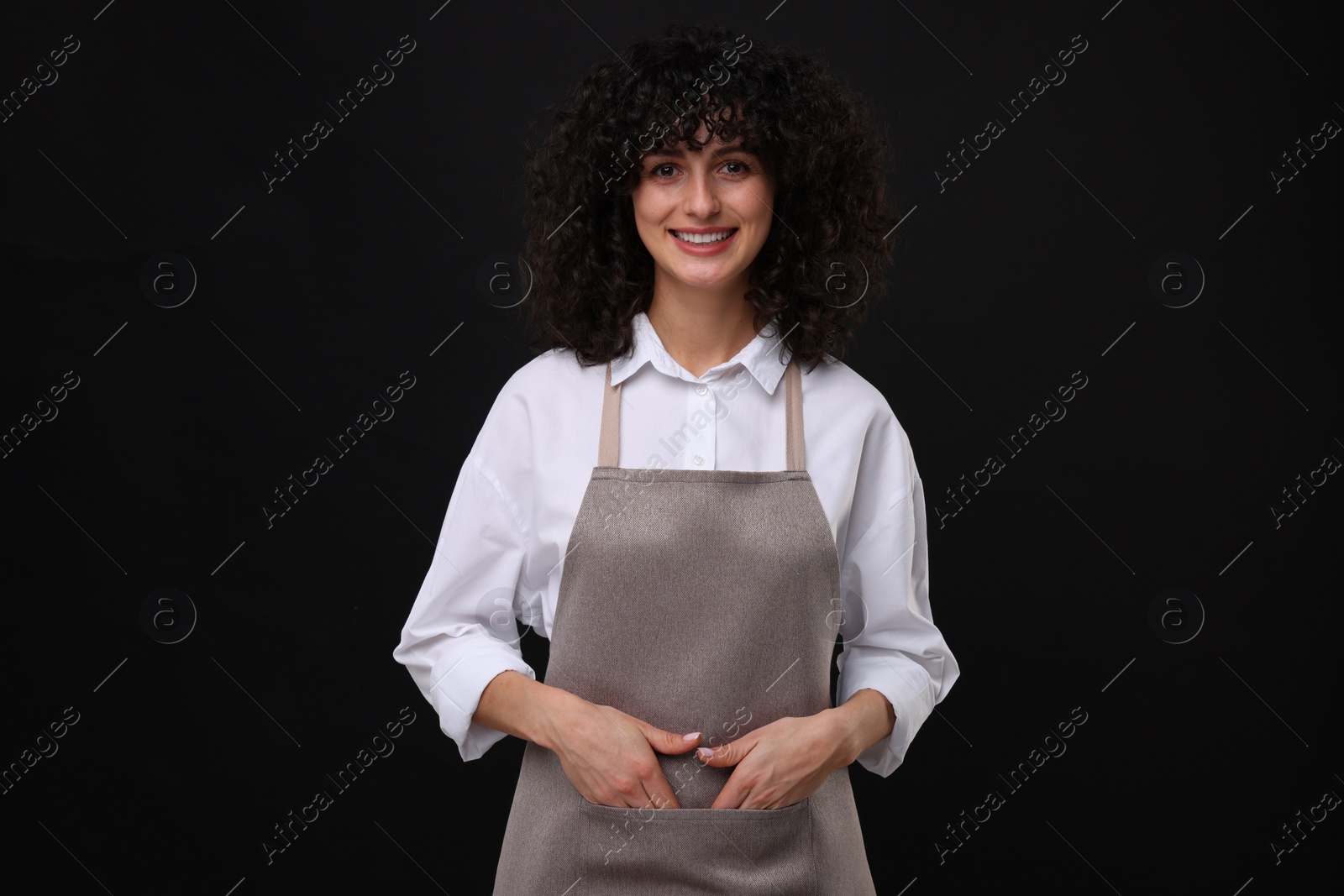 Photo of Happy woman wearing kitchen apron on black background. Mockup for design